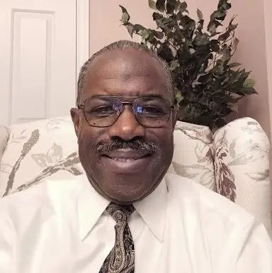 Richard in formal attire, floral background.