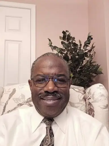 CEO Of Wellspring Insurance Benefits, Richard's in white shirt and tie & floral background.